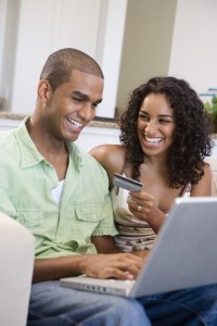 Couple using laptop while holding a credit card