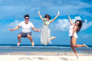 three people on the beach jumping in the air for a photo