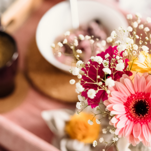 a breakfast tray with coffee, cereal, and a bouqet of pink flowers.
