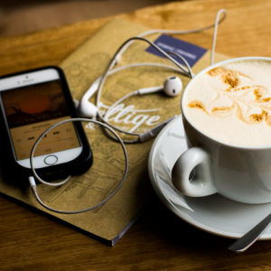 an iphone with headphones and a cup of coffee