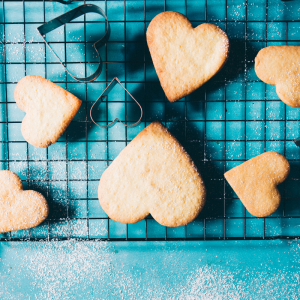 a tray of heart shaped sugar cookies on a blue countertop