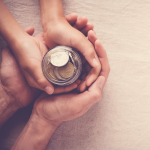 Parent holding child's hands holding a jar full of money