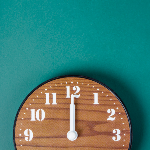 a wood clock laying on a teal background