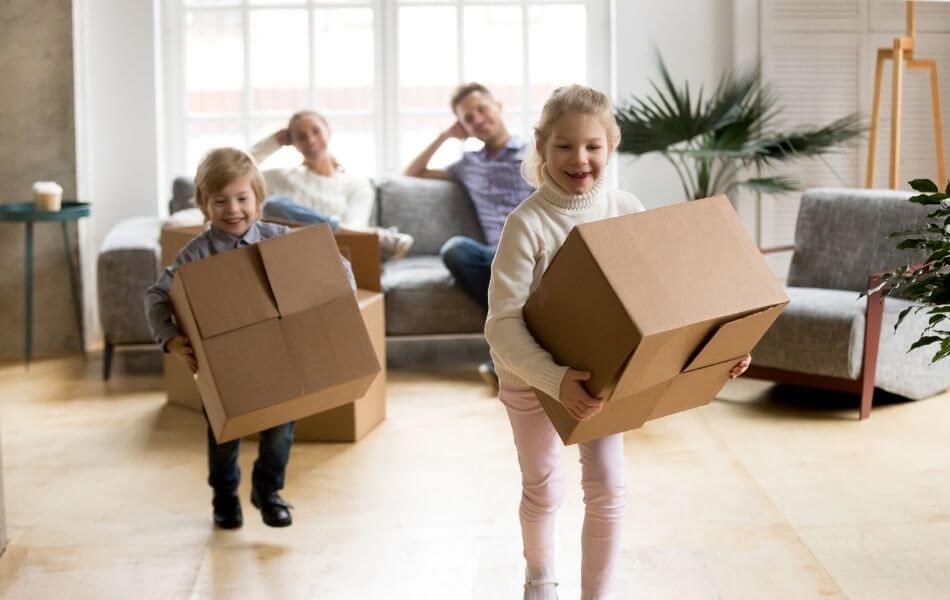 Family in new home. Kids carrying boxes