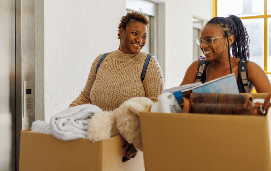 Two girls holding moving boxes