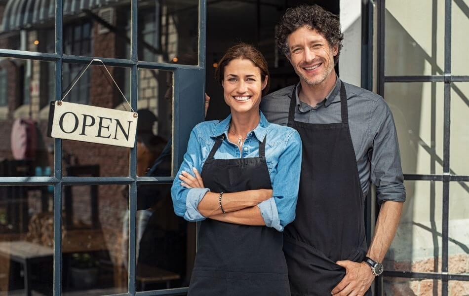 Business owners in front of 'open' sign