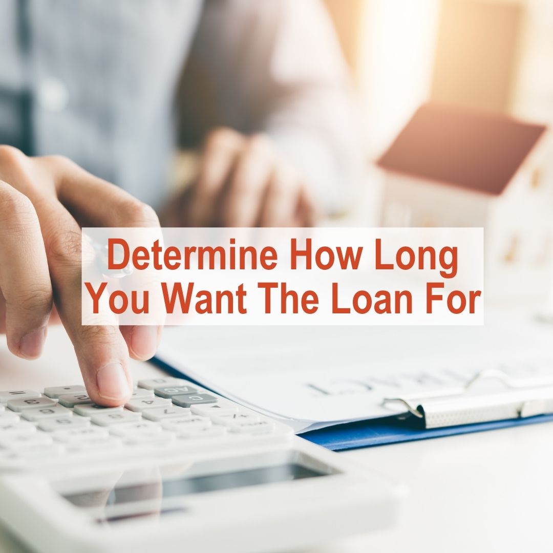 Person typing on a calculator at desk | Determine How Long You Want The Loan For