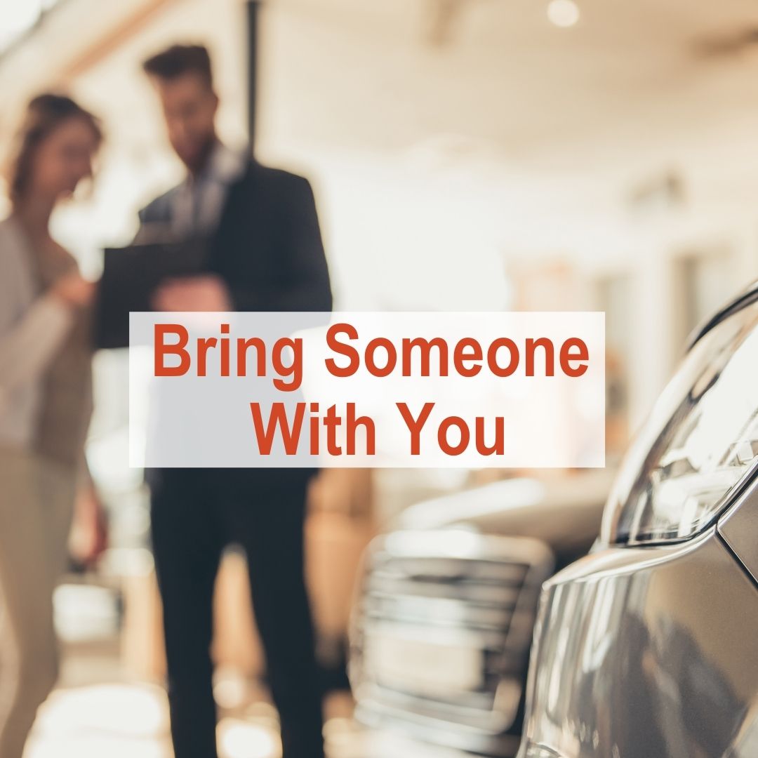 two people standing by car in dealership | Bring Someone With You