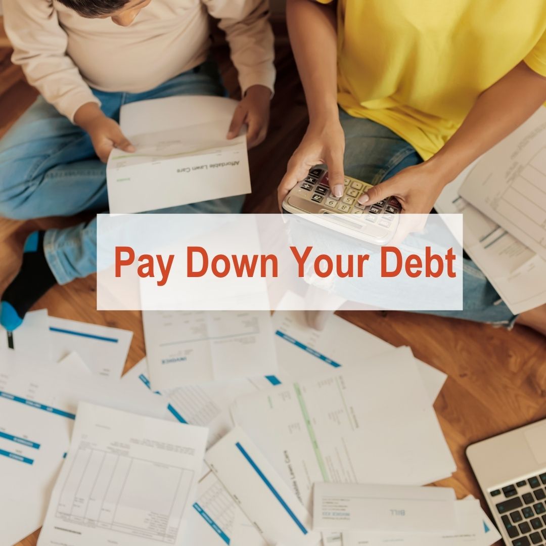Two people sitting on floor with papers everywhere holding a calculator | Pay Down Debt