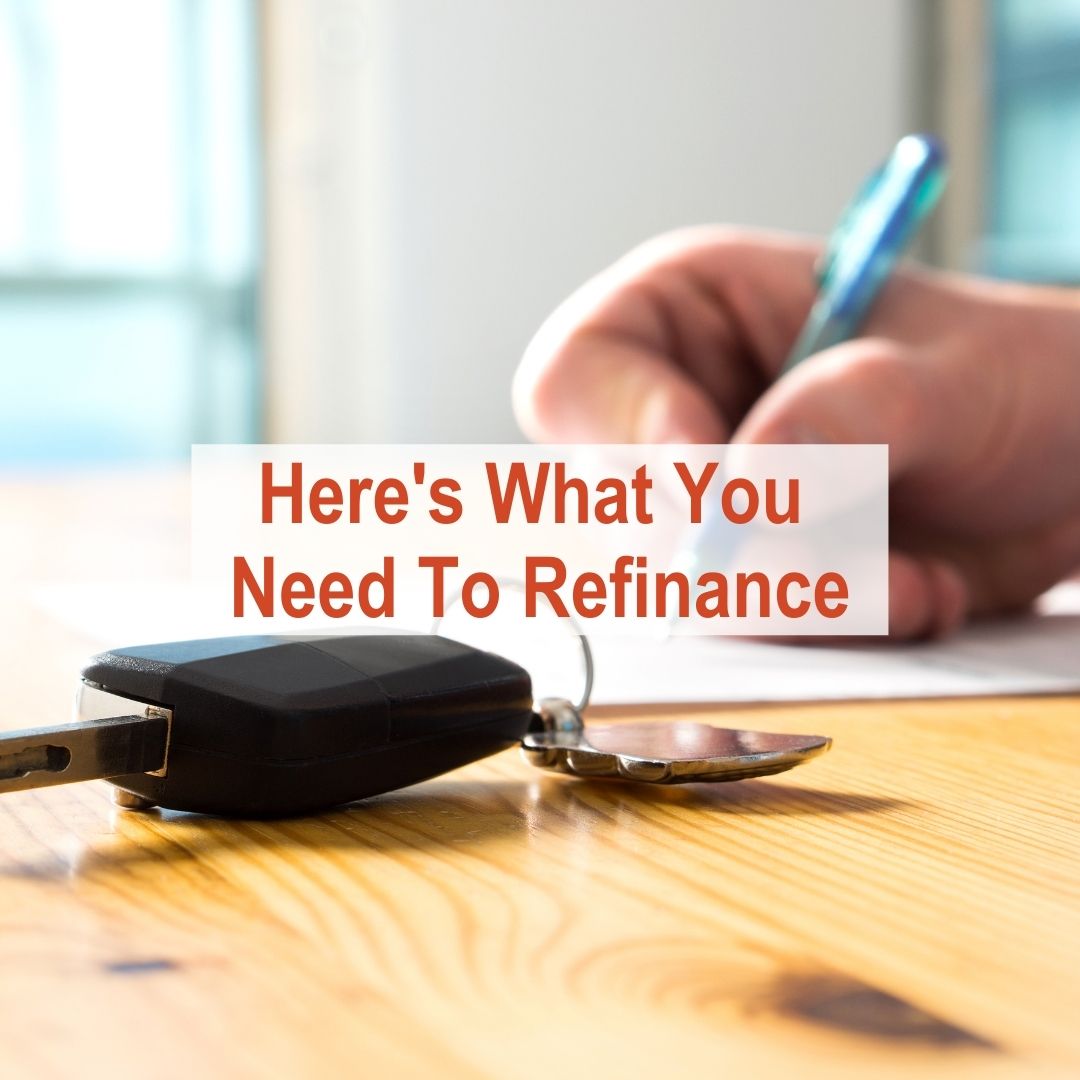 Person writing on paper with car keys next to hand | Here's What You Need To Refinance