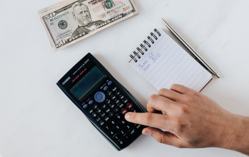 Track Your Money - A note pad, money and a calculator sit on a desk