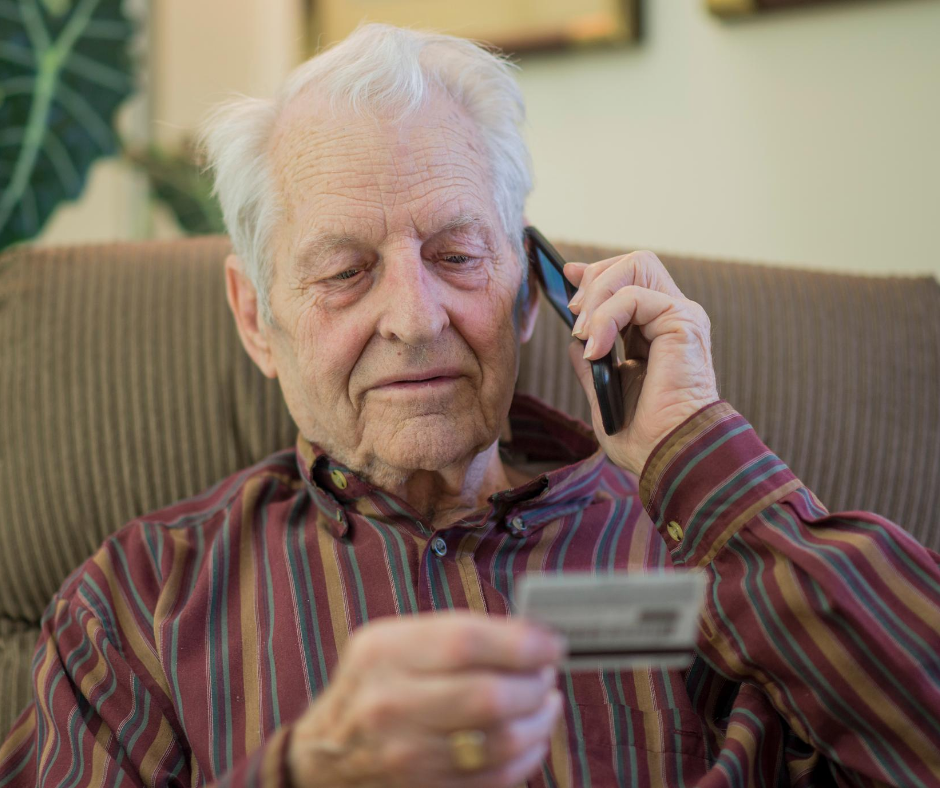 Elderly man talking on phone holding credit card